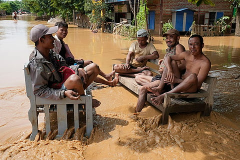 Myanmar floods: Residents sit on a bench on a flooded road