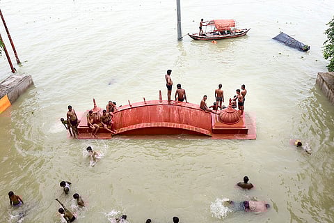 People bathe in the swollen Ganga river in Prayagraj
