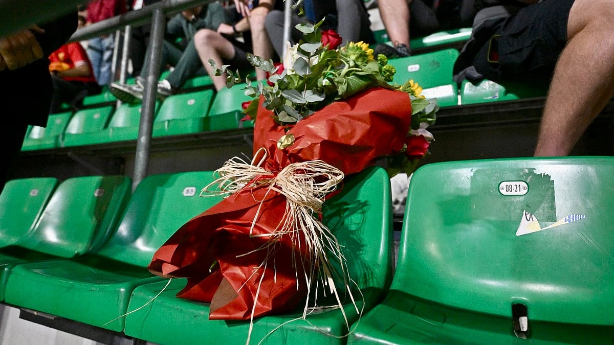 Representatives from Liverpool and AC Milan place flowers on the seat of supporter Philip Dooley. - X/ @LFC