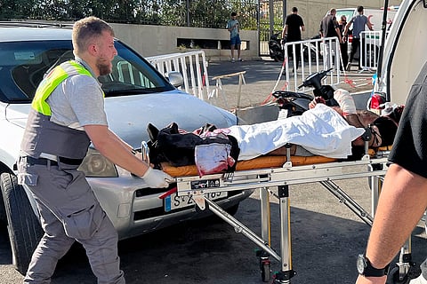 Lebanon Pager Explosions: A Civil Defense first-responder carries a wounded man in Beirut