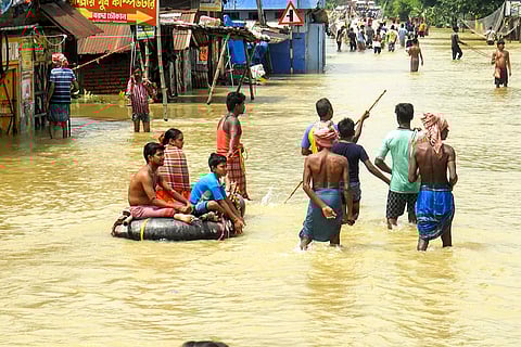 Bengal floods: People wade through floodwaters at a flood-affected area