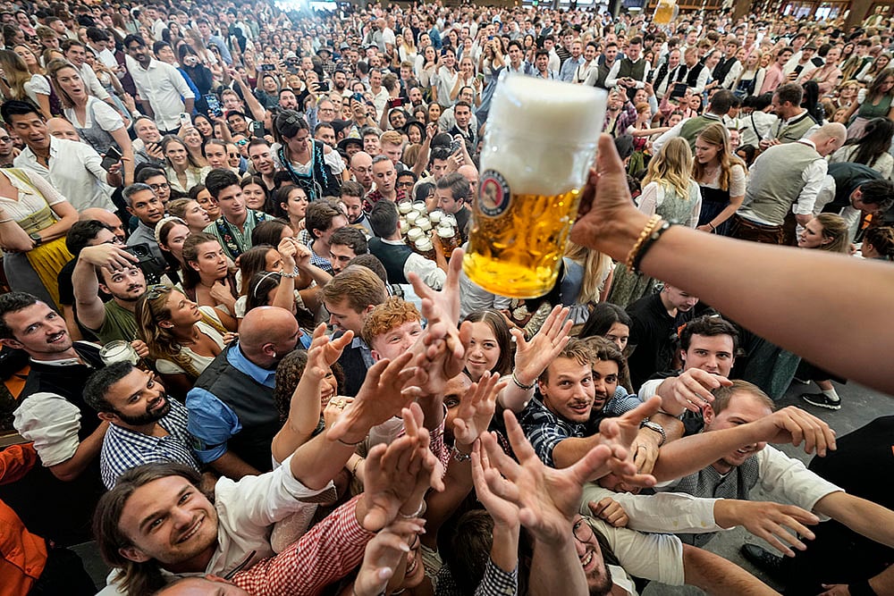 | Photo: AP/Matthias Schrader : Oktoberfest Opening: Festival goer reach out for the first glasses of beer