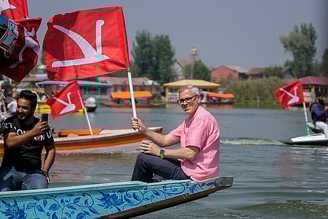 Omar Abdullah, holds his party flag during an election rally at Dal Lake