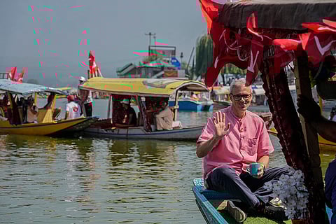 Omar Abdullah sits on the deck of a boat during an election rally at Dal Lake