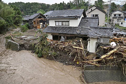 Japan Floods: Debris is piled near damaged houses along a river running through Wajima