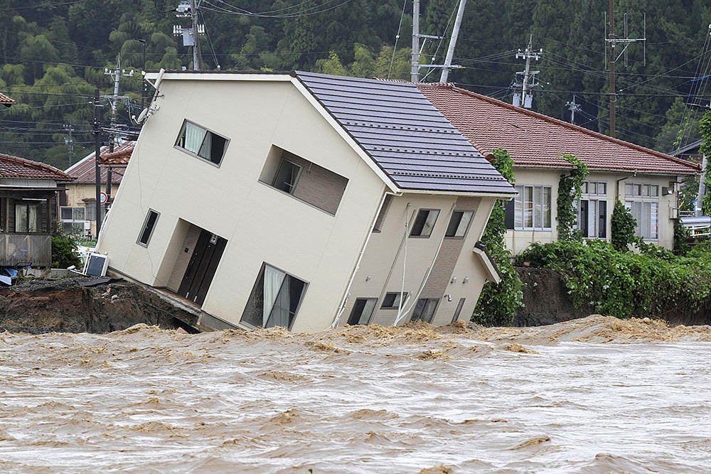 Japan Floods: A house leans as a swollen river undermines the ground in Suzu - | Photo: Kasumi Fukudome/Kyodo News via AP
