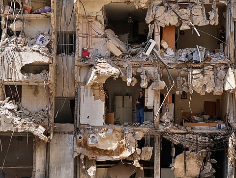 A man watches rescuers sift through the rubble as they search for people still missing at the site of Friday's Israeli strike in Beirut's southern suburbs, Monday, Sept. 23, 2024