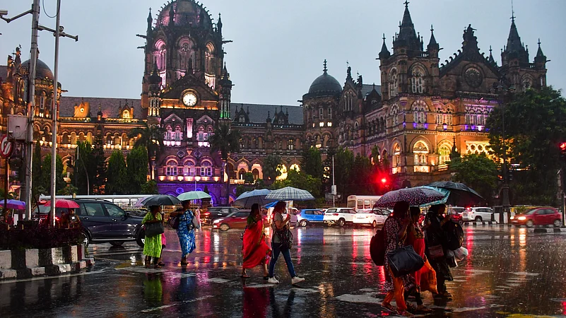 Pedestrians cross a road amid rain, in Mumbai