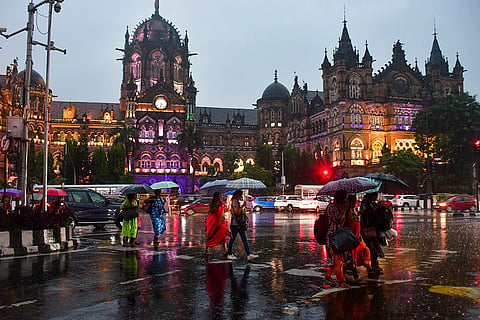 Rains in Mumbai: Pedestrians cross a road amid rain