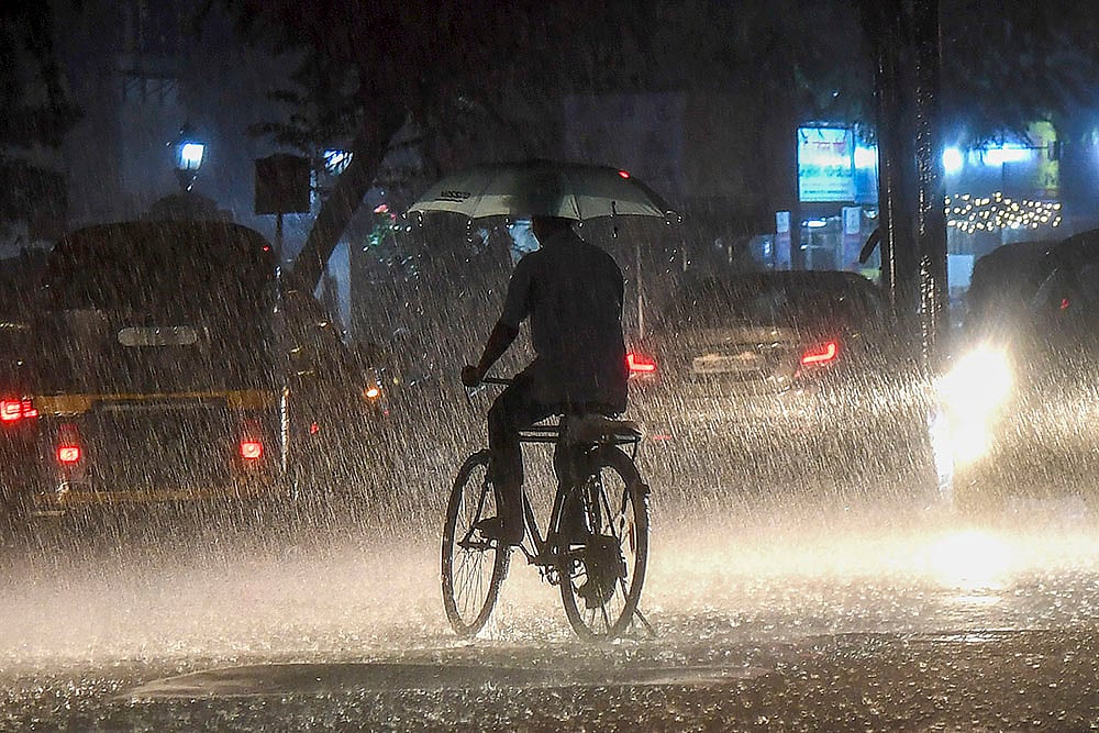 Rains in Mumbai: A man holds an umbrella while riding a cycle - | Photo: PTI