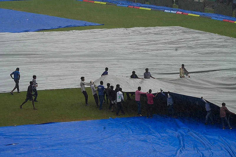 Weather: Ground staff cover the ground during rains in Kanpur