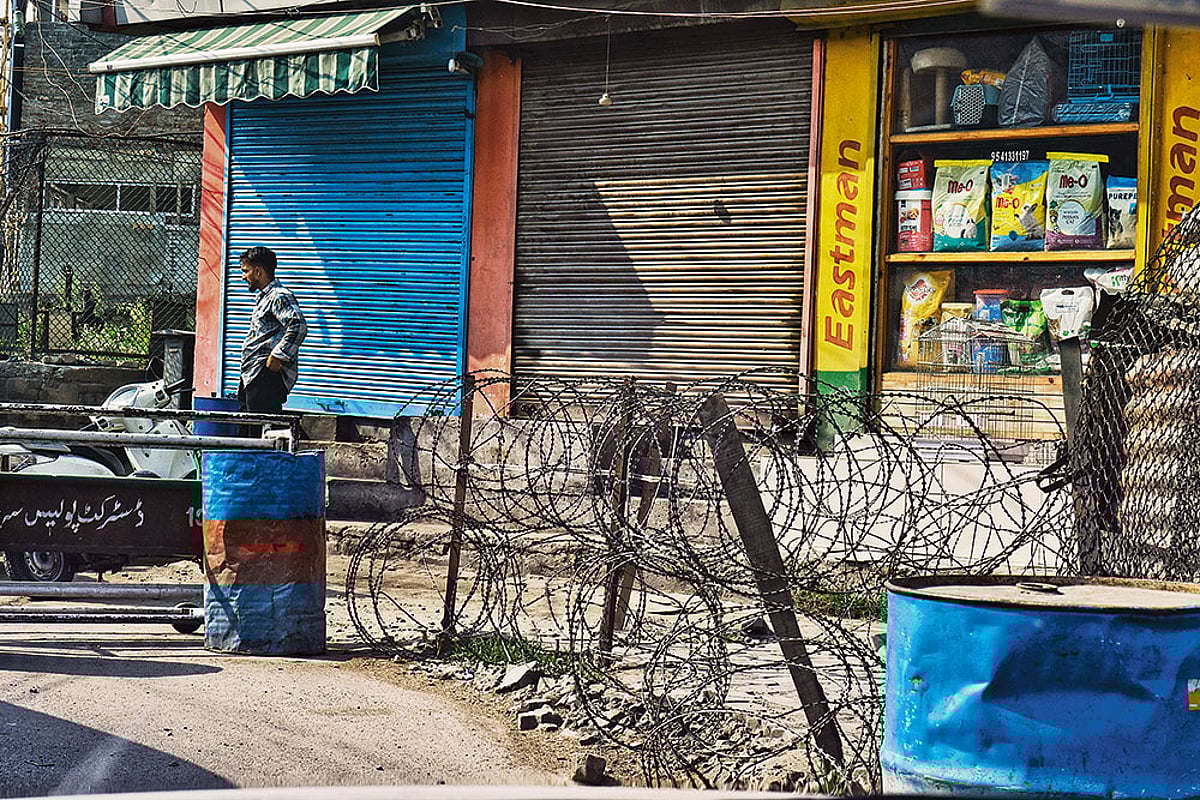 A man standing next to a checkpoint in downtown Srinagar