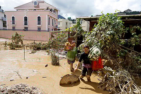 Nepal Floods: Women walk with their belongings in the mud in Kathmandu