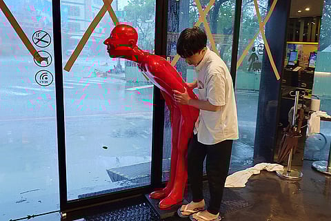 Taiwan Typhoon Krathon: A hotel staff prepares to move a human figure from the doorway