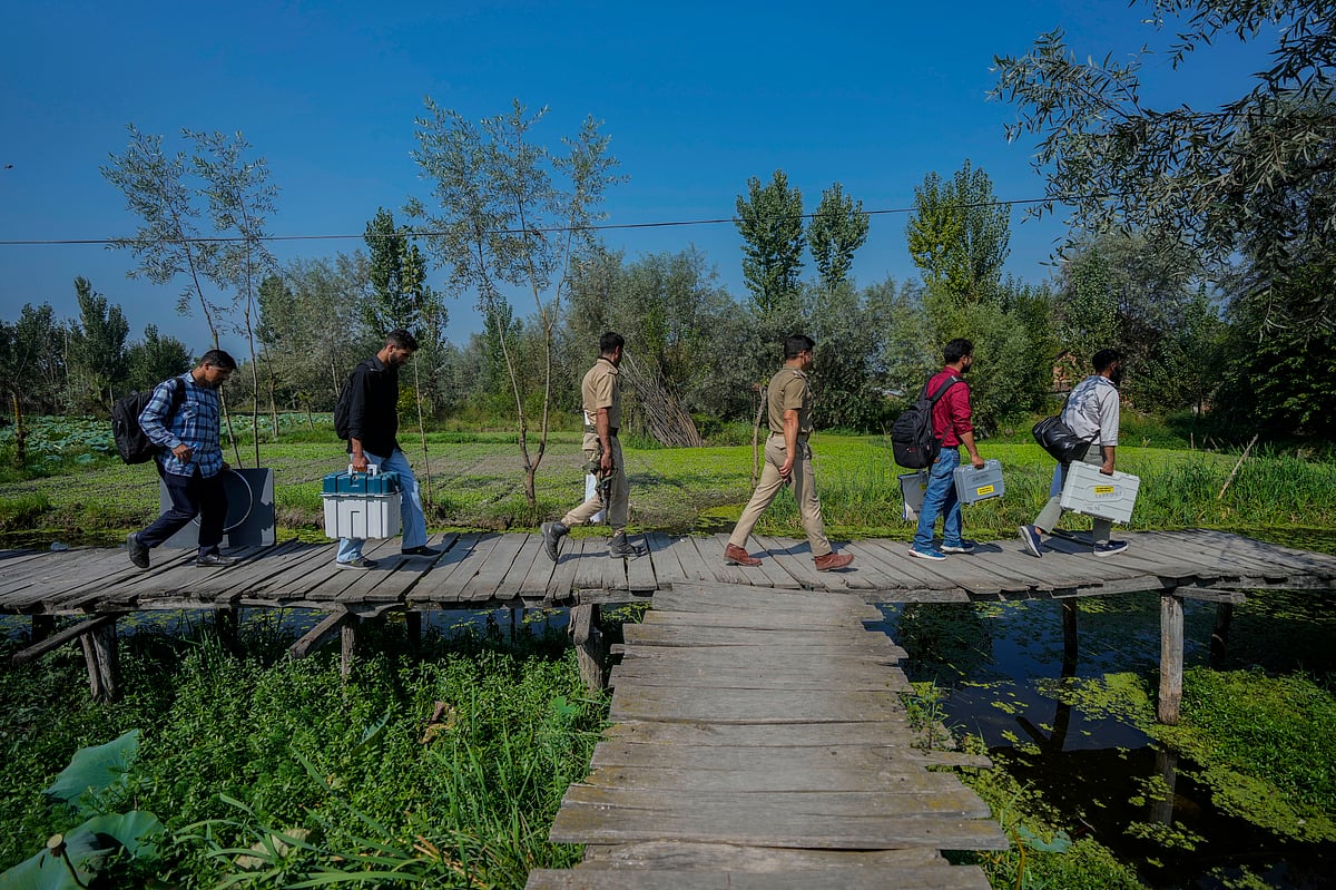 Associated Press : Polling officials and police walk on a wooden bridge towards a polling station in the interior of Dal Lake