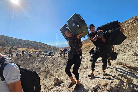 Mideast Tensions: People carry their luggage as they cross on foot into Syria