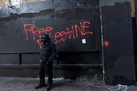 A man stands in front of "Free Palestine" graffiti during a rally in downtown Los Angeles on October 5, 2024,