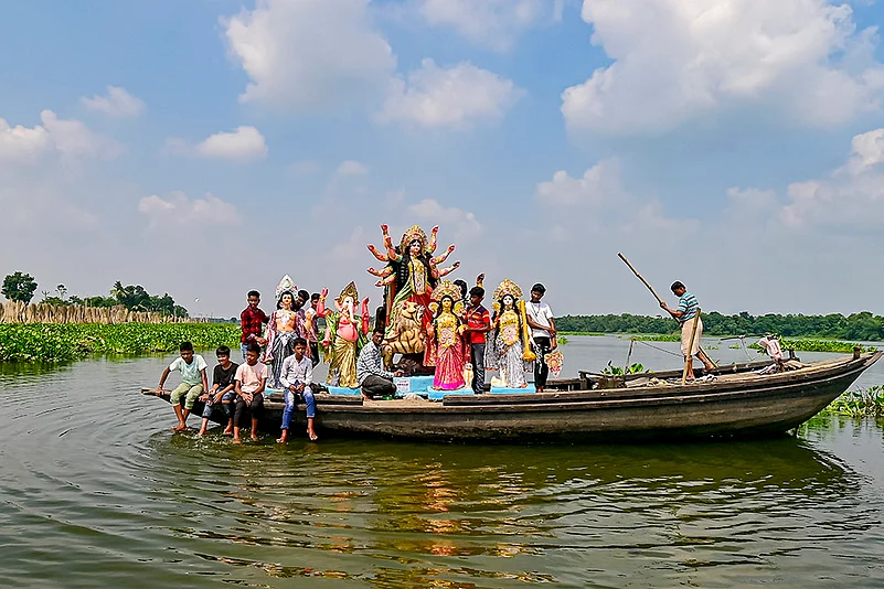 An idol of Goddess Durga being taken to a puja pandal on a boat in Nadia