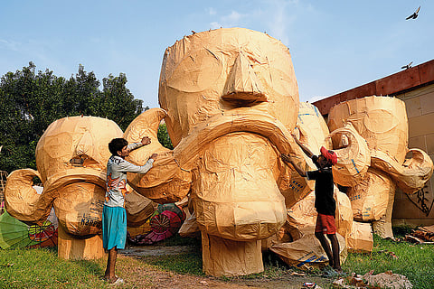 Artisans fix a moustache made on a giant visage of Raavan