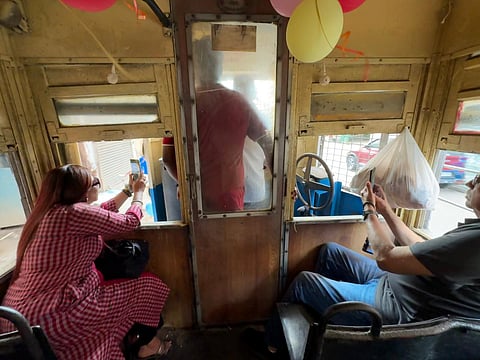 While the tram makes journey through the iconic city of Kolkata, people take out their camera to capture the experience.