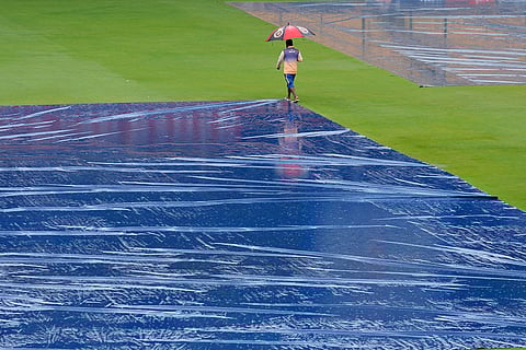 IND Vs NZ 1st Test: A groundsman walks past the pitch area covered with plastic sheets