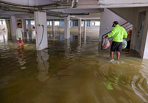 Residents walk through waterlogged area after water entered an apartment complex following heavy rainfall, in Bengaluru, Wednesday