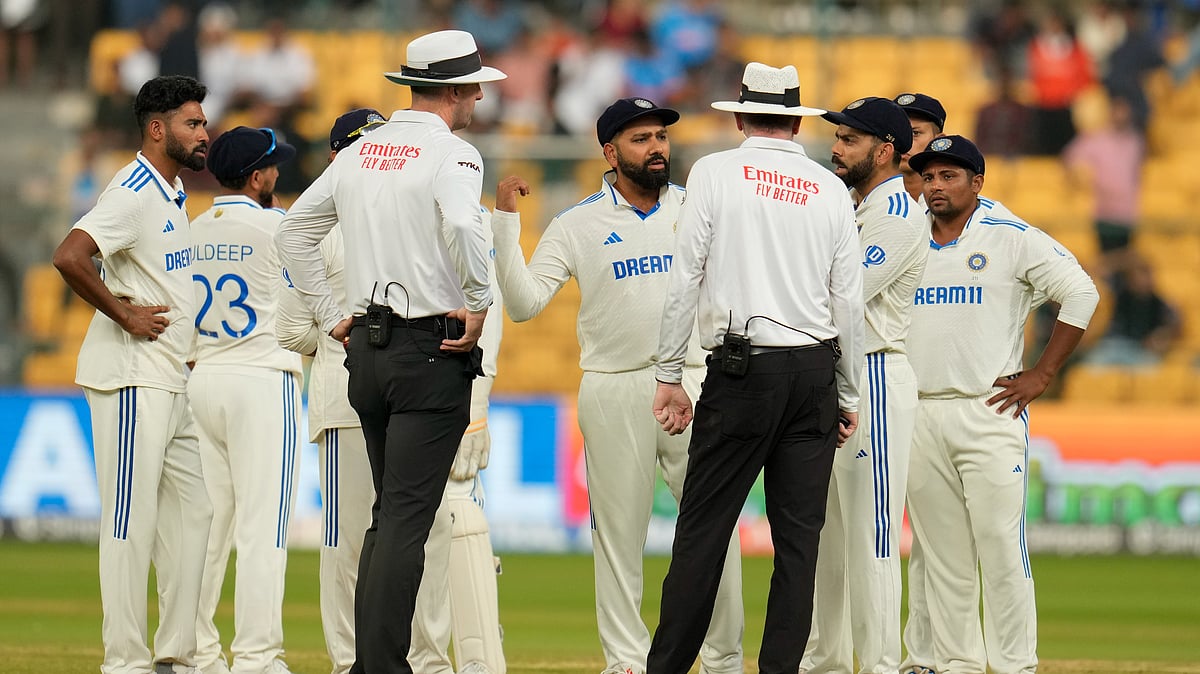 AP Photo/Aijaz Rahi : India's captain Rohit Sharma, centre, speaks to the umpires after bad light stopped play on day four of the first cricket test match between India and New Zealand at the M.Chinnaswamy Stadium.