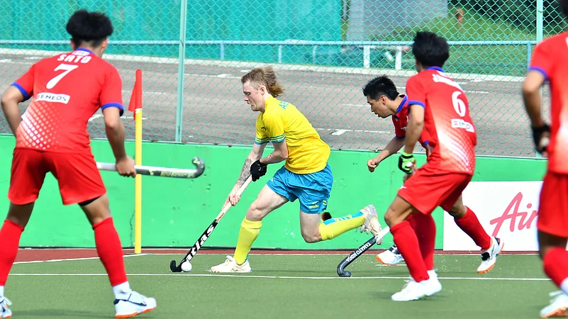 japan hockey players trying to tackle australian player X asian hockey federation