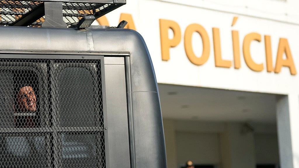 AP : A fan of Uruguay's Penarol team looks out from a police bus upon arriving at a police station after being detained for fighting with police on the beach in Rio de Janeiro, Wednesday, Oct. 23, 2024.