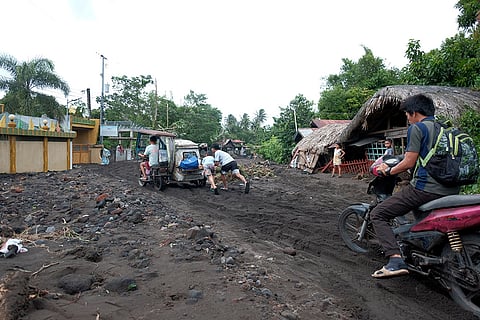 Tropical Storm Trami: Residents negotiate a road covered with volcanic mud