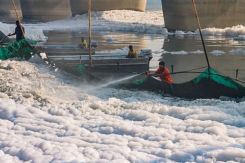 Workers remove toxic foam in Yamuna river