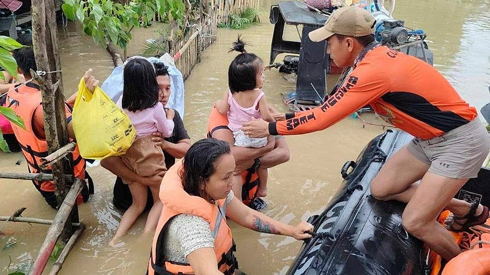 | Photo: Philippine Coast Guard via AP : Philippine Coast Guard rescue residents trapped in their home after floods