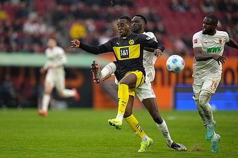Bundesliga soccer: Dortmund's Jamie Bynoe-Gittens, centre, challenges for the ball with Augsburg's Chrislain Matsima