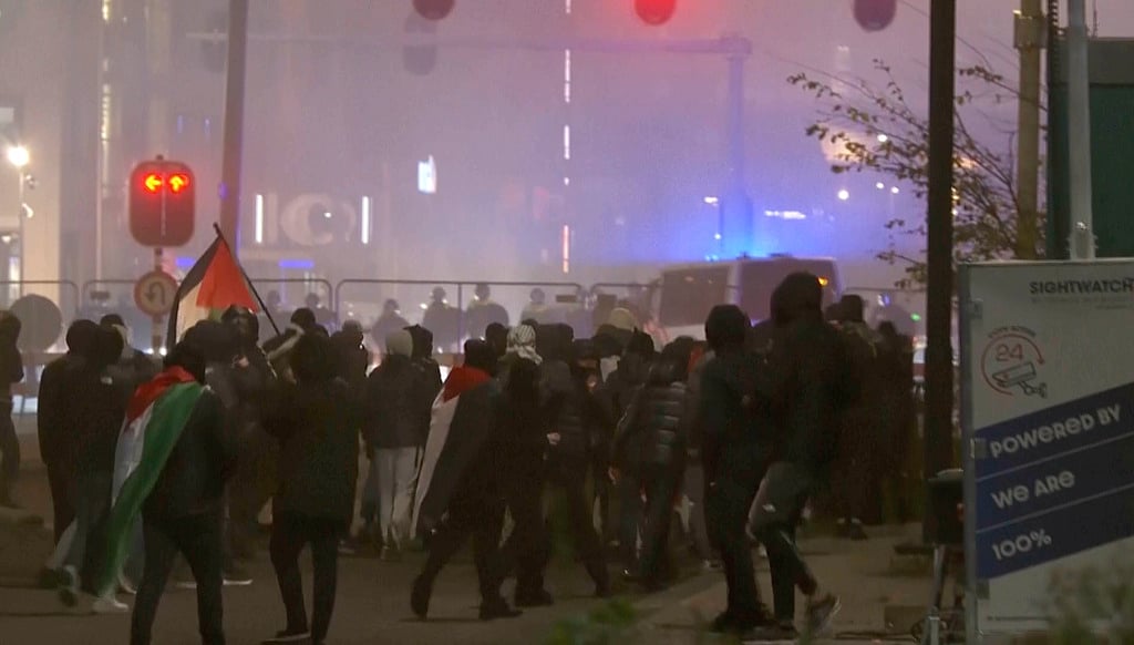 RTL Nieuws via AP : In this image taken from video, a group of pro-Palestinian protesters walk toward police line, with police vans driving in the background, near the football stadium in Amsterdam, Netherlands.