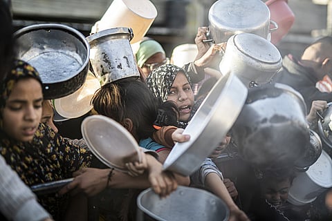 Palestinians in Rafah, Gaza, queue to receive food distributed by aid organizations