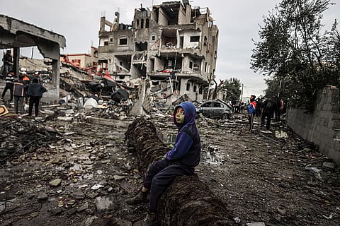A boy sits on a fallen tree amid rubble after Israeli airstrike hit civil residential area in al Maghazi refugee camp, Gaza on December 25, 2023