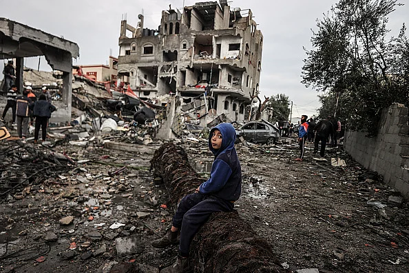 A boy sits on a fallen tree amid rubble after Israeli airstrike