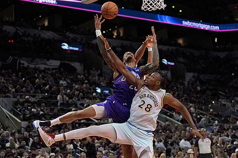 NBA: Jazz forward John Collins, top, is blocked by Spurs center Charles Bassey (28)