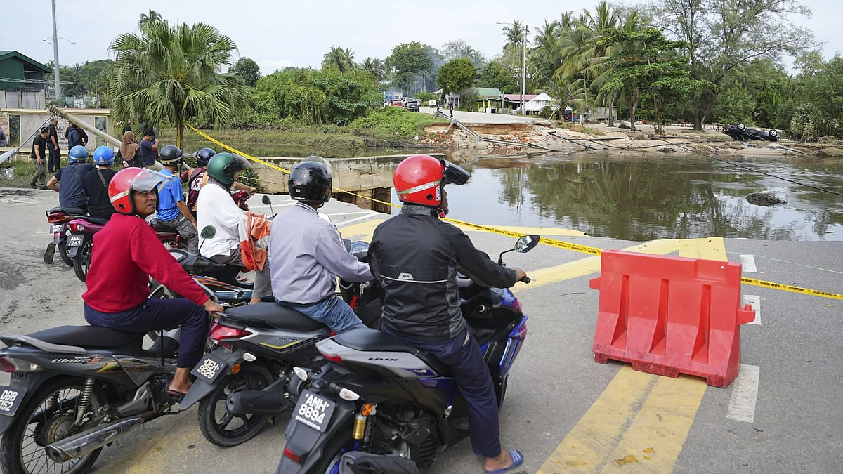 AP : Motorists survey a road damaged by a flood in Tumpat, on the outskirts of Kota Bahru in Kelantan state on the east coast of Malaysia.