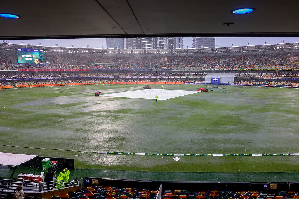 AP Photo/Pat Hoelscher : General view of covers on the pitch as it rain during play on day one of the third cricket test between India and Australia at the Gabba in Brisbane, Australia, Saturday, Dec. 14, 2024.