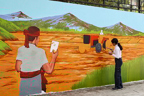 Artists paint a wall in Delhi