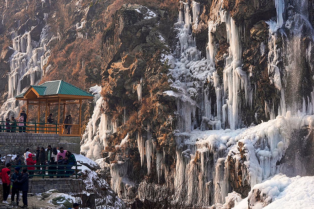 | Photo: PTI/S Irfan : Cold wave in Kashmir valley: Visitors take pictures of the frozen Drung waterfall.