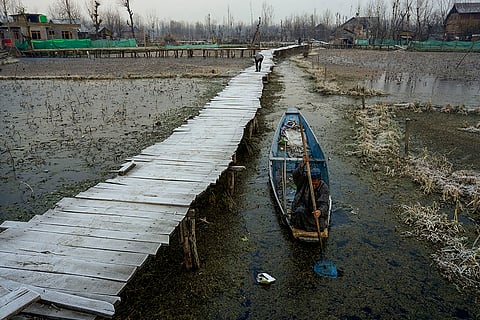 Cold wave in Kashmir valley: A man uses an oar to cut through the thin layer of ice.