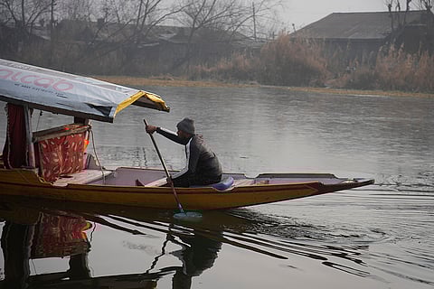 Cold wave in Kashmir valley: Boatman rows his boat near the frozen surface of the water.