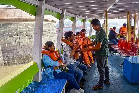 A passenger is helped to wear a life jacket