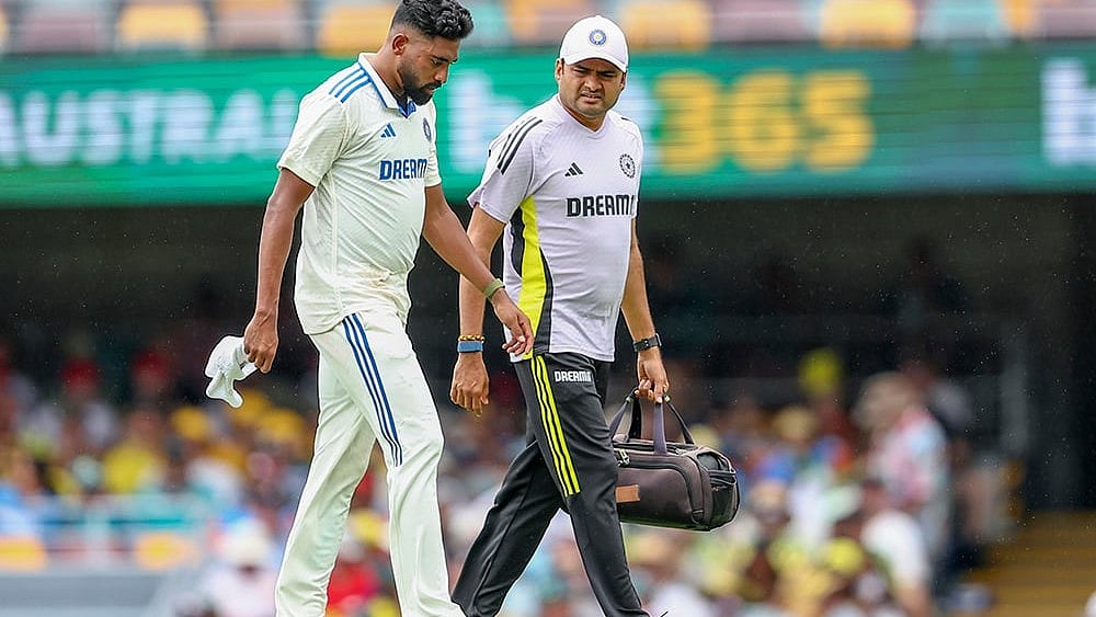 | Photo: AP/Pat Hoelscher : India Vs Australia, 3rd Test Day 2: India's Mohammed Siraj, left, walks off the field after an injury 