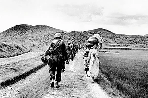 | Photo: Getty Images : Two Faces of a War: A line of US Army soldiers file past a group of Korean women and children during the 1950-1953 Korean War