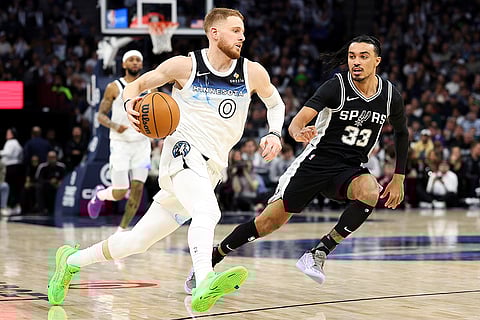 NBA 2024-25: Timberwolves guard Donte DiVincenzo (0) works around Spurs guard Tre Jones