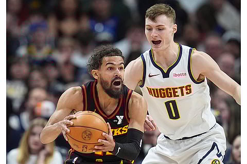 NBA 2024-25: Hawks guard Trae Young, left, looks to pass the ball as Nuggets guard Christian Braun defends