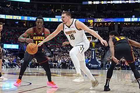 NBA 2024-25: Nuggets center Nikola Jokic, center, pursues the ball while driving between Hawks forwards